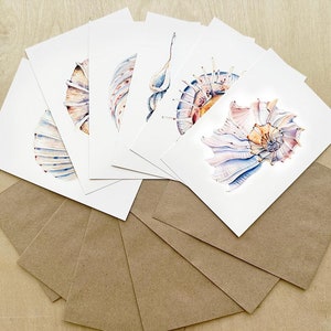 Peut inclure: Ensemble de six cartes de v&oelig;ux vierges illustrant des coquillages &agrave; l'aquarelle. Les cartes sont blanches avec des enveloppes brunes.