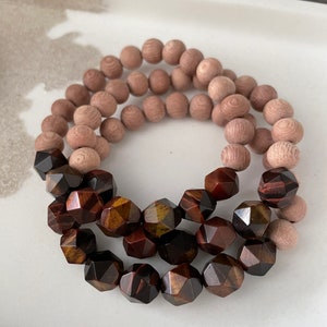 Op de afbeelding: Een armband gemaakt van bruine houten kralen en gefacetteerde tijgeroogkralen.