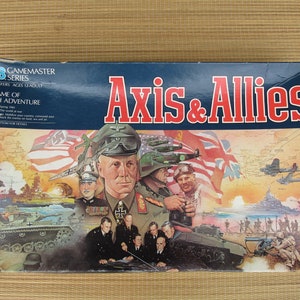 May include: A rectangular board game box for Axis & Allies, featuring a colorful illustration of military figures, tanks, ships, and aircraft from World War II. The title Axis & Allies is printed in large red letters against a dark blue background.