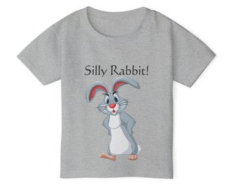 May include: A gray t-shirt featuring a cartoon rabbit with red-tipped ears, a red nose, and a white belly. The text "Silly Rabbit!" is printed above the rabbit. The shirt is made of a soft material.