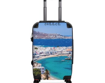 May include: A rolling suitcase featuring a vibrant image of Greece. The suitcase has a black frame, a retractable handle, and four wheels. The image depicts a coastal town with white buildings, turquoise water, and the word "GREECE" at the top.