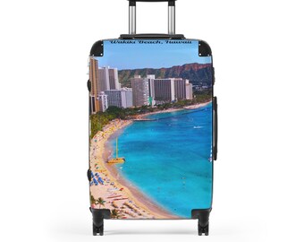 May include: A rolling suitcase featuring a vibrant image of Waikiki Beach, Hawaii. The design showcases a turquoise ocean, sandy beach, and a cityscape with hotels and palm trees. The text "Waikiki Beach, Hawaii" is printed at the top.