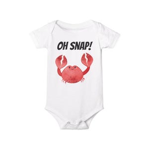 May include: White baby onesie with a red cartoon crab and the text "OH SNAP!" printed on the front.