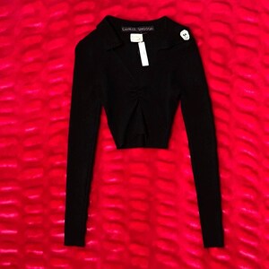 Könnte beinhalten: Ein schwarzes, langärmeliges Crop-Top mit Kragen und gerafften Details in der Mitte. Das Oberteil hat einen Knopf auf der Schulter und der Markenname "CAMILLE SMOOGH" ist auf dem Kragen zu sehen. Ein weißes Etikett hängt am Ausschnitt.