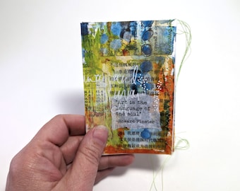 Puede incluir: Una página de diario de arte de técnica mixta con una cita de Howard Finster: "El arte es el lenguaje del alma." La página está decorada con pintura colorida, texto y costuras.