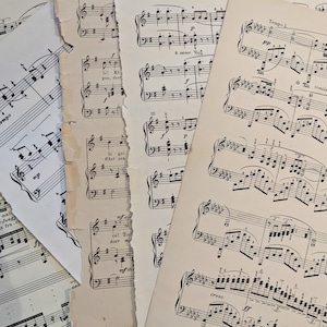 May include: A close-up of several sheets of music with handwritten notes and musical notation. The music is torn and aged, giving it a vintage look.