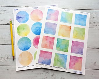 Puede incluir: Dos hojas de papel de pegatinas con diseños de acuarela. Una hoja tiene 6 pegatinas redondas con diferentes diseños de acuarela. La otra hoja tiene 9 pegatinas cuadradas con diferentes diseños de acuarela. El texto en las hojas dice "Assortment 6a" y "Assortment 6b".