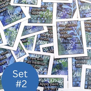 May include: A collection of art journaling cards with blue, green, and white abstract designs. Each card features handwritten text prompts and instructions for mixed media art techniques. A blue circle with "Set #2" is in the foreground.