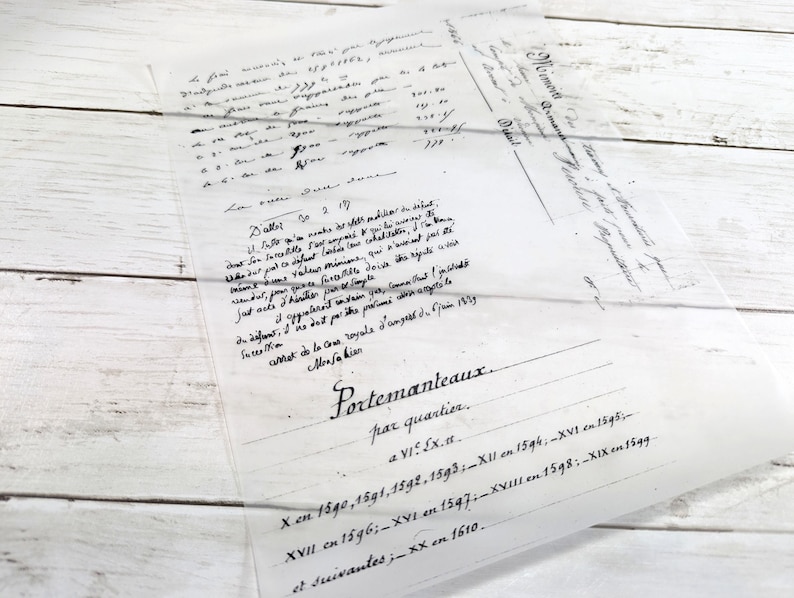 May include: A translucent sheet of paper with handwritten text in black ink, featuring the word "Portemanteaux" and dates like "1590" and "1610." The paper is laid on a white wooden surface.