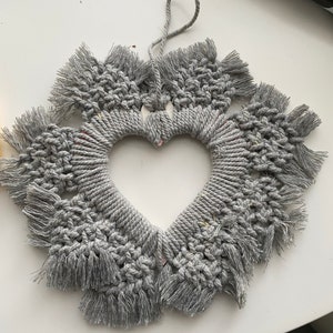 Może przedstawiać: Szary wiszący makramowy w kształcie serca z frędzlami.