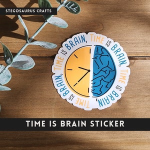 May include: A white sticker with a blue and yellow clock design. The clock is divided in half, with one half showing a brain and the other half showing a clock face. The text "TIME IS BRAIN, TIME IS BRAIN" is written around the clock. The sticker is on a wooden surface.