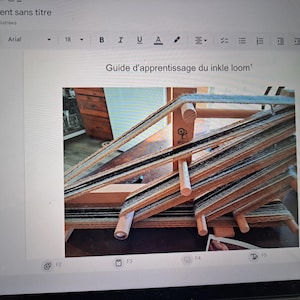 Peut inclure: Un métier à tisser inkle en bois avec des fils de chaîne noirs, marron et crème. Le texte "Guide d'apprentissage du inkle loom" est visible. Le métier est conçu pour le tissage, avec une structure détaillée.