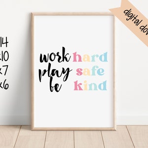 May include: A printable wall art print with the text "work hard play safe be kind" in black script font. The words "hard", "safe", and "kind" are in colorful block letters with pink, blue, and yellow accents. The print is framed in a light wood frame.