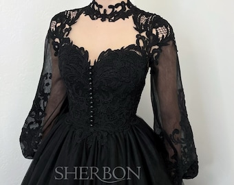 May include: A black tulle ball gown with long sleeves and a high neckline. The sleeves and bodice are adorned with intricate black lace. The dress has a full skirt and a fitted bodice. The dress is labeled "Sherbon".