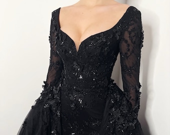 Può includere: Un abito lungo nero a maniche lunghe con scollatura profonda e gonna in tulle. L'abito è ricoperto di ricami floreali neri.