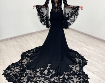 Puede incluir: Un vestido negro de manga larga con un corpiño de encaje y una falda fluida. El vestido tiene un cuello alto y una superposición de encaje en las mangas. La falda está ajustada a las caderas y se ensancha en la parte inferior.