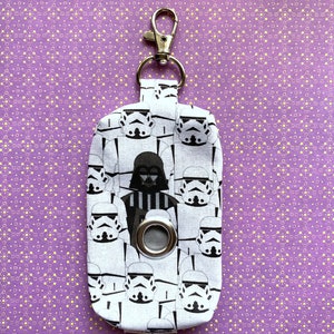 Puede incluir: Porta bolsas de caca de tela blanca con un estampado de Star Wars en blanco y negro con Darth Vader y Stormtroopers. El porta bolsas tiene un clip plateado y un ojal plateado.