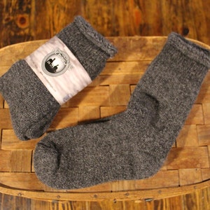 May include: Two pairs of grey wool socks, one pair folded and one pair laid out flat. The socks are made of a soft, warm material and are perfect for cold weather.