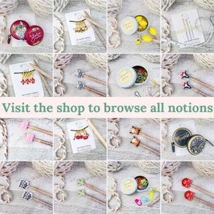 Pu&ograve; includere: Una collezione di accessori per maglieria, tra cui segnapunti, metri a nastro e spilli decorativi. Gli articoli sono disposti su una superficie bianca con filato e il testo "Visit the shop to browse all notions".