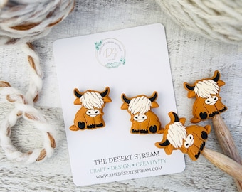 May include: Four brown and white Highland Cow hair clips. The hair clips are on a white card with the text "The Desert Stream Craft. Design. Creativity. www.thedesertstream.com"