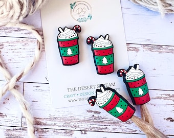 May include: Four Christmas-themed drink charms with whipped cream, a candy cane, and a green Christmas tree design. The charms are red, green, and white. The charms are on a white card with the text "THE DESERT STREAM BOUTIQUE".