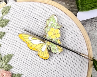 May include: A yellow and green butterfly embroidery kit with a needle and thread. The butterfly is surrounded by green leaves and flowers.