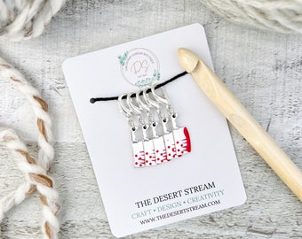 May include: Set of five silver stitch markers shaped like a white butcher knife with red blood splatter. The markers are on a white card with the text "THE DESERT STREAM" and "CRAFT • DESIGN • CREATIVITY" and "WWW.THEDESERTSTREAM.COM".