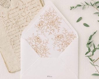 May include: White envelope with a gold floral design on the inside. The word "White" is printed on the front. Also shown are a vintage letter, green leaves, and a gold wax melting spoon.