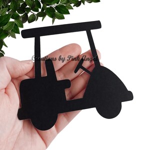 This image showcases a golf cart paper cutout held in a hand.  The golf cutout is made from black cardstock. These golf cutouts are great for events, party decorations, and scrapbooking.