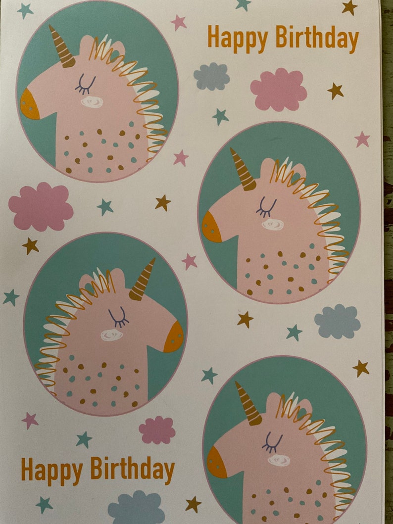 Puede incluir: Una tarjeta blanca con un esquema de color turquesa, verde y rosa. La tarjeta presenta cuatro unicornios rosas con cuernos y crines dorados. Los unicornios est&aacute;n rodeados de estrellas doradas y nubes rosas y azules. El texto "Happy Birthday" est&aacute; escrito en letras doradas en la parte superior e inferior de la tarjeta.