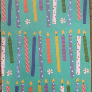 May include: A teal background with a repeating pattern of colorful birthday candles with white polka dots, stripes, and confetti. The candles have a yellow flame.