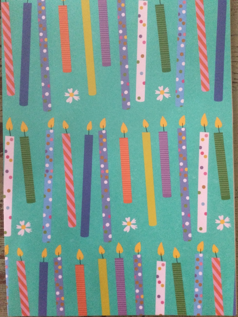 May include: A teal background with a repeating pattern of colorful birthday candles with white polka dots, stripes, and confetti. The candles have a yellow flame.