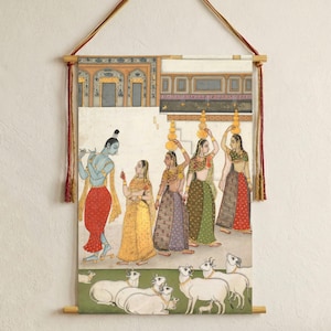 Könnte beinhalten: Indische Miniaturmalerei, die eine blauhäutige Figur zeigt, die Flöte spielt, umgeben von Frauen, die Töpfe auf dem Kopf tragen. Das Kunstwerk zeigt leuchtende Farben, eine grüne Landschaft und weiße Kühe. Das Gemälde ist auf Holzstäben montiert und mit einer roten und goldenen Schnur aufgehängt.
