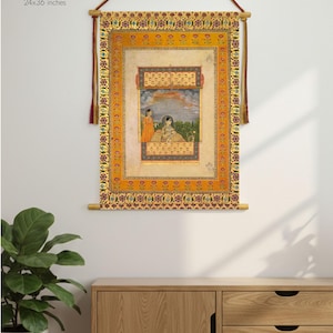 May include: Cotton wall hanging featuring a detailed illustration with figures in a garden setting. The artwork is framed with ornate borders in shades of orange and gold. Available sizes include 12x18, 16x24, 20x30, and 24x36 inches. Ready to hang.