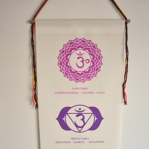 May include: A white banner with purple and white illustrations of the crown chakra and third eye chakra. The crown chakra is a lotus flower with the symbol Om in the center. The third eye chakra is a triangle with the symbol Om in the center and two eyes above it. The text below each chakra reads "crown chakra - understanding - oneness - peace" and "third eye chakra - openness - clarity - intuition".