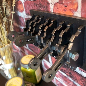 May include: Three industrial-style light switches with metal gears and levers. The switches are mounted on a black metal plate against a brick wall.