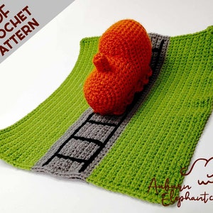 May include: A crochet pattern for a train engine and track. The engine is orange and the track is green and gray. The pattern is available as a PDF download.