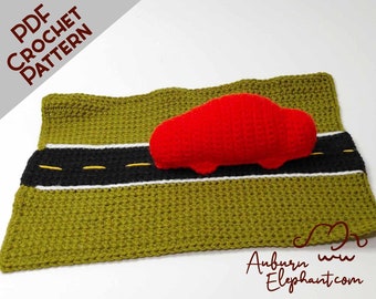 Może przedstawiać: Wzór na szydełku na czerwony samochód na zielonej drodze. Wzór jest dostępny jako plik PDF do pobrania. Tekst "PDF CROCHET PATTERN" znajduje się w lewym górnym rogu obrazu.
