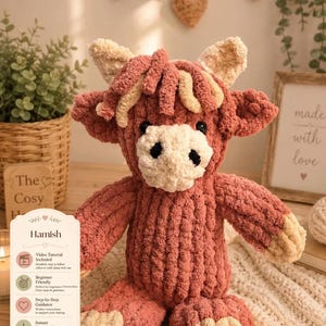 May include: A handmade, plush Highland cow named Hamish, in shades of pink and cream. The stuffed animal has a textured, soft appearance, with a white face and black eyes. The image includes a sign with the name "Hamish" and details about a video tutorial.