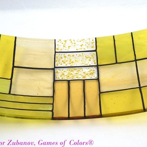 Puede incluir: Un plato de servir de vidrio amarillo con un dise&ntilde;o geom&eacute;trico. El plato est&aacute; hecho de vidrio transparente con acentos amarillos y blancos. El plato est&aacute; ligeramente curvado y tiene un dise&ntilde;o moderno.