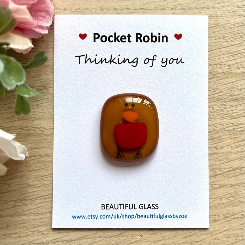 Pu&ograve; includere: Una piccola figurina di vetro di un pettirosso, con un corpo marrone, petto rosso e becco arancione. La figurina &egrave; su una carta bianca con il testo "Pocket Robin Thinking of you" e "BEAUTIFUL GLASS www.etsy.com/uk/shop/beautifulglassbyzoe".
