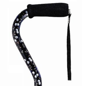 May include: A black walking cane with a golf ball and tee design. The cane has a black foam handle and a black wrist strap.