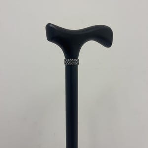 May include: A black wooden walking stick with a decorative silver band around the handle.
