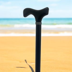 May include: A black wooden walking cane with a curved handle and a decorative band near the top.