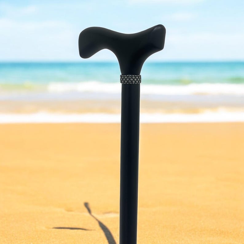 May include: A black wooden walking cane with a curved handle and a decorative band near the top.