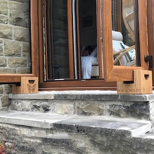 May include: Wooden window props with a butterfly design and the text "DON & WENDY" are shown. The props are holding open a brown window. The window is set in a stone wall.