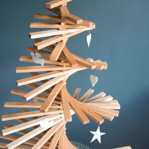 May include: A wooden Christmas tree made of stacked slats in a spiral shape. The tree is decorated with white heart and star ornaments.