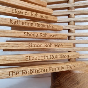 May include: A wooden family tree with the names "Eleanor Robinson", "Katherine Robinson", "Sheila Robinson", "Simon Robinson", "Elizabeth Robinson", and "The Robinson Family Tree" engraved on it.