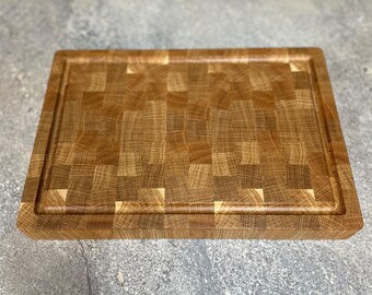 May include: A large, rectangular wooden cutting board made of oak with a checkered pattern. The board has a thick, raised edge.