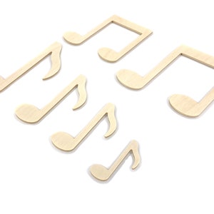 May include: Six wooden music note shapes in various sizes, all in a light brown color. The notes are arranged in a random pattern on a white background.